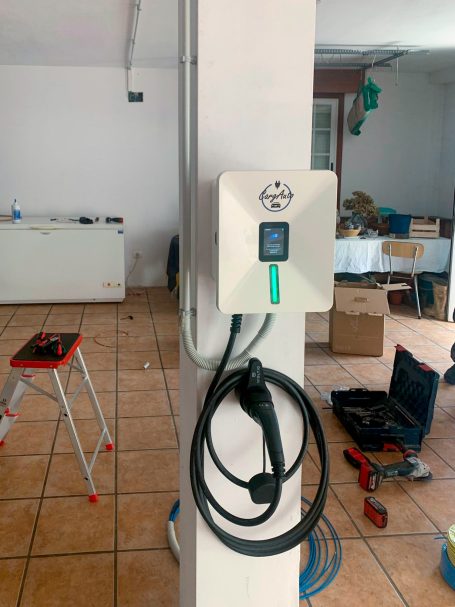 Punto de carga para vehículo eléctrico montado en una pared, con cable enrollado.