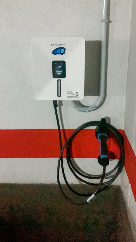 Cargador eléctrico montado en la pared con un cable enrollado.