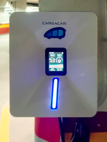 Estación de carga para vehículos eléctricos con pantalla y luz indicadora.