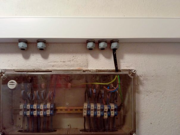 Caja de conexiones eléctricas con cables organizados y canalización en la parte superior.