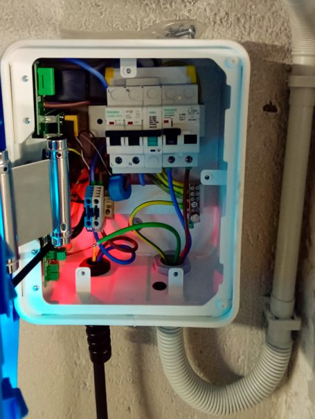 Caja de conexiones eléctrica con cables de colores y luces LED en su interior.