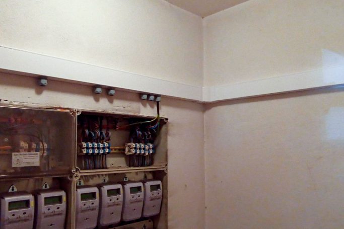 Cuatro contadores eléctricos en una pared blanca, con cables visibles arriba.