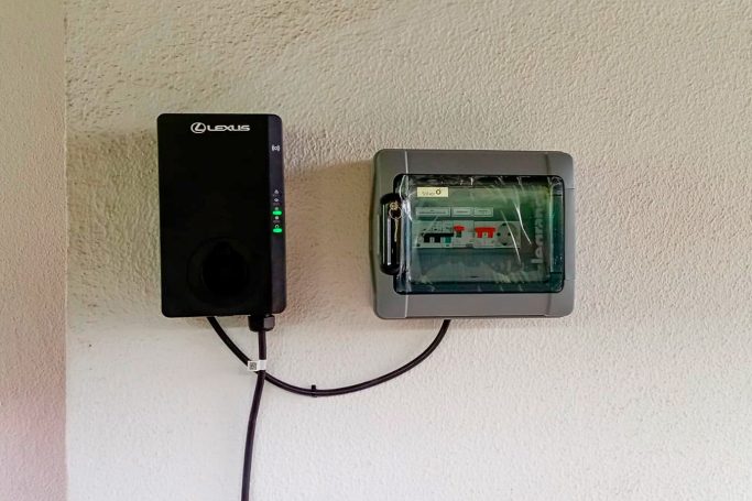 Dispositivo electrónico negro conectado a una caja transparente en la pared.